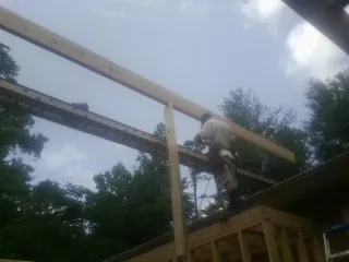 Carpenter setting a ridge beam over a new addition frame in Sparta